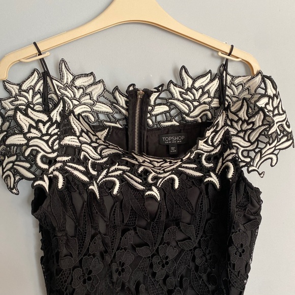 It’s a black and white off shoulder top with an embroidered flower design. - Picture 5 of 7